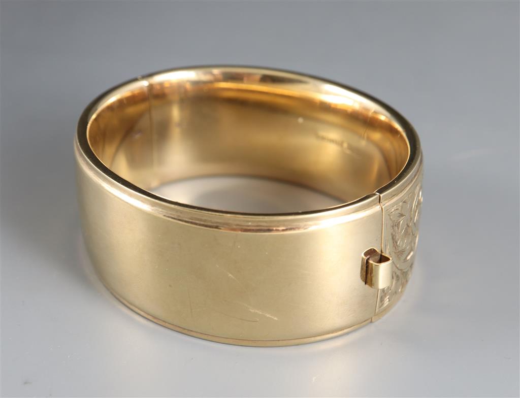 A late 1950s engraved 9ct gold hinged bangle,
